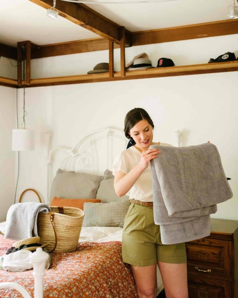 A woman folding organic beach towels to pack in her beach bag.