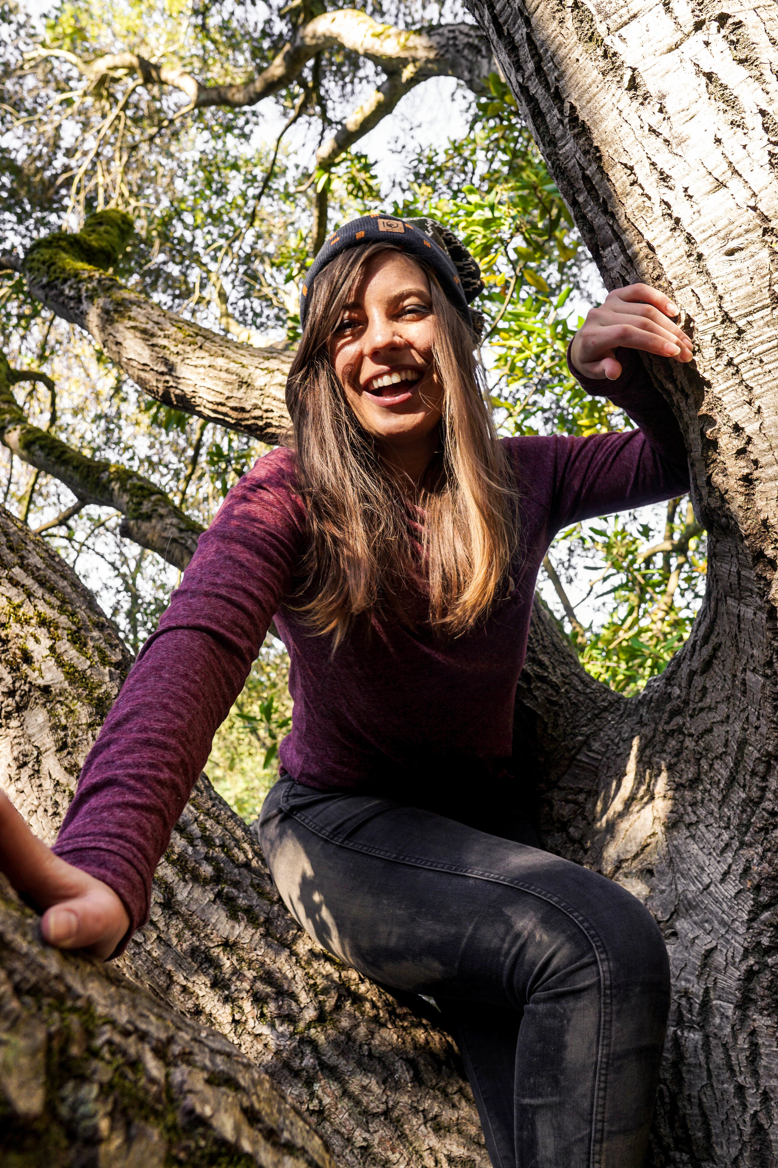 a smiling woman posting in a tree wearing her day hiking essentials.